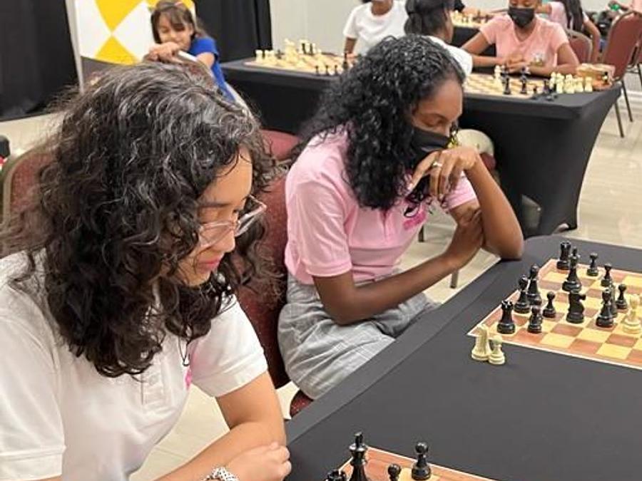 Women and girls competing over chess boards at a Guyana tournament.