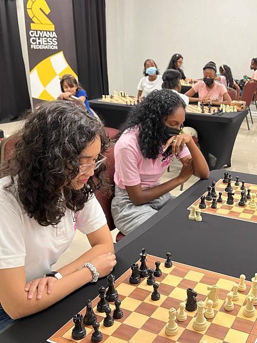 Women and girls playing chess during a community training day.